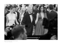 Black-and-white fine art photography print of Michael Douglas at the 76th Cannes Film Festival projected on a giant screen, with blurry silhouettes of photographers, white border, and caption.