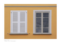 Color fine art photograph of two windows side by side: a real window with white shutters and a painted window. Concept: Real or Fake.