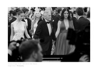 Black-and-white fine art photography print of Michael Douglas at the 76th Cannes Film Festival projected on a giant screen, with blurry silhouettes of photographers, white border, and caption.
