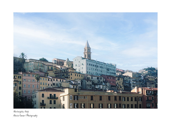 A scene of Ventimiglia in December featuring colorful traditional Ligurian houses, a bright blue sky, and white clouds. Fine art photography for A5 fine art prints.